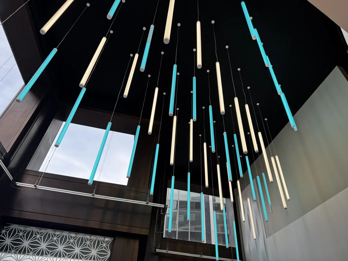 Primark Oxford Street foyer feature lighting: cascading vertical tubes in cream and brand-matched teal.